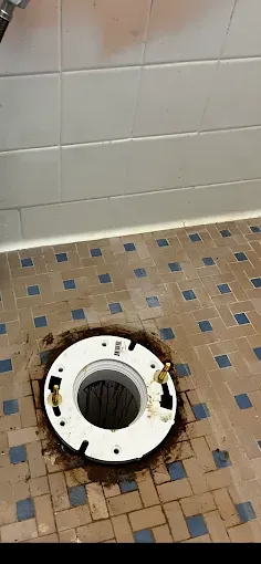 Toilet flange installed on a tiled floor in a bathroom.