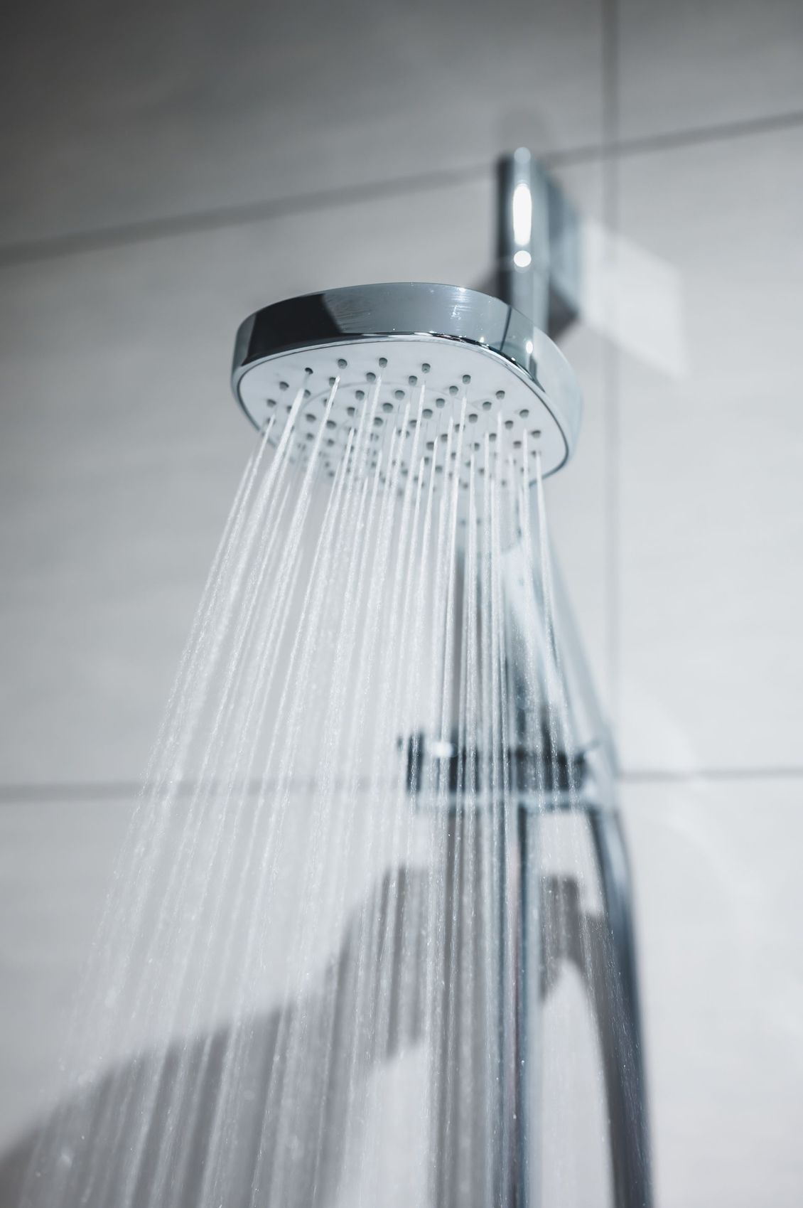 Showerhead spraying water in a tiled bathroom.