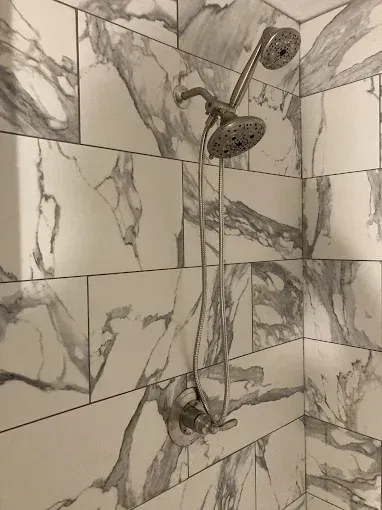 Shower with marbled white and gray tile. Silver showerhead and fixtures.