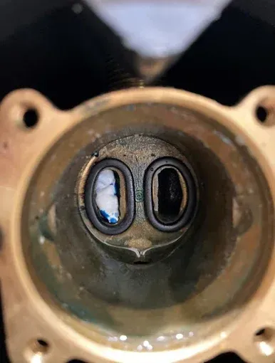 Close-up of a brass fitting with two oval openings; visible are dark circles inside, reflecting light.