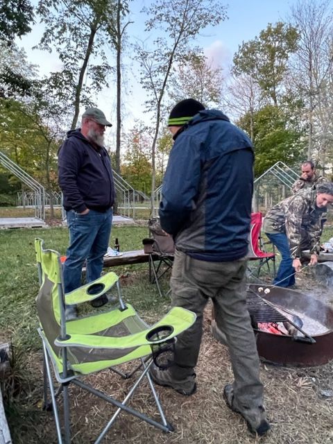 a group of men are standing around a fire pit .