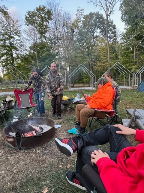 a group of people are sitting around a fire pit .