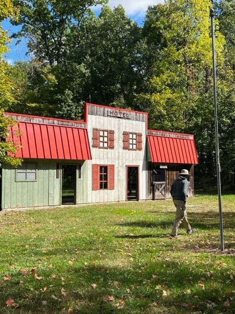 a man is walking in front of a small house with a red roof .