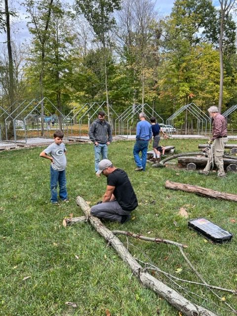 a group of men are working on a log in a field .