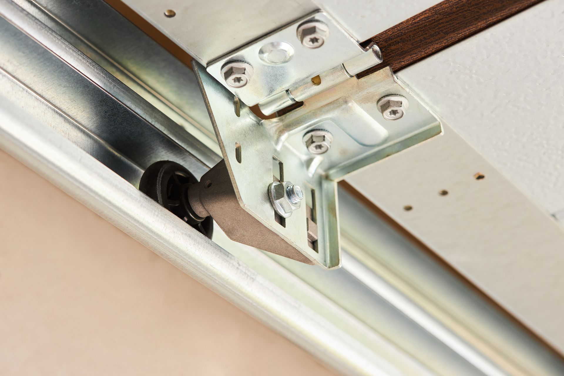 Close-up of a metal garage door hinge and roller track on a white ceiling.