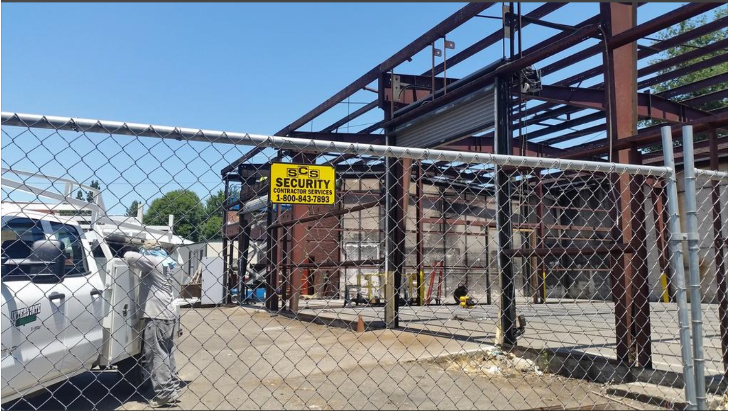 A chain link fence surrounds a building under construction.