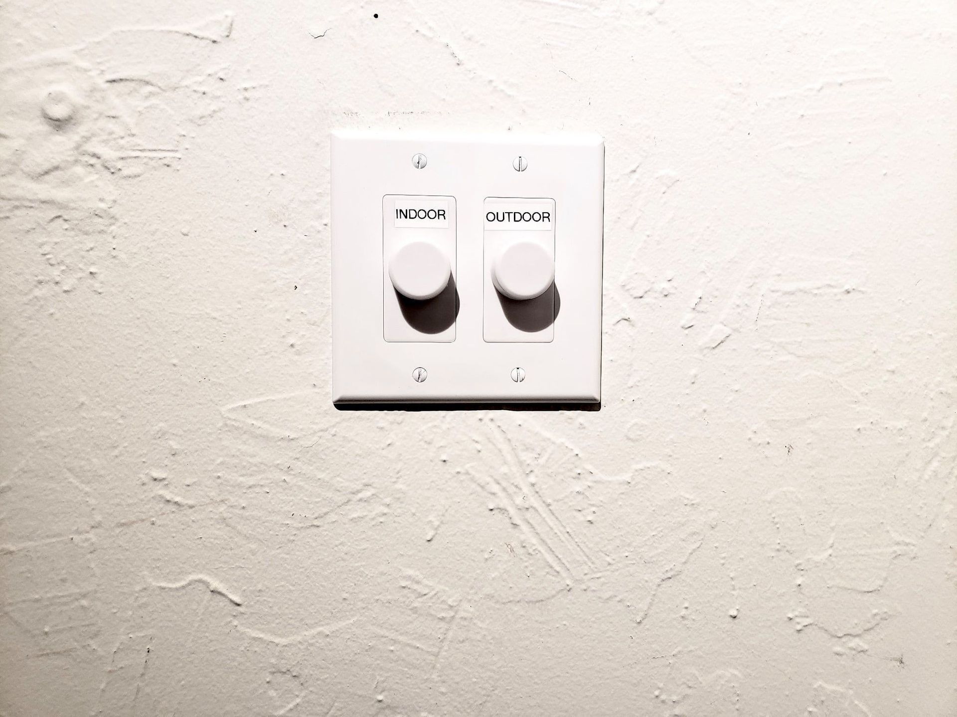 A white light switch on a white wall