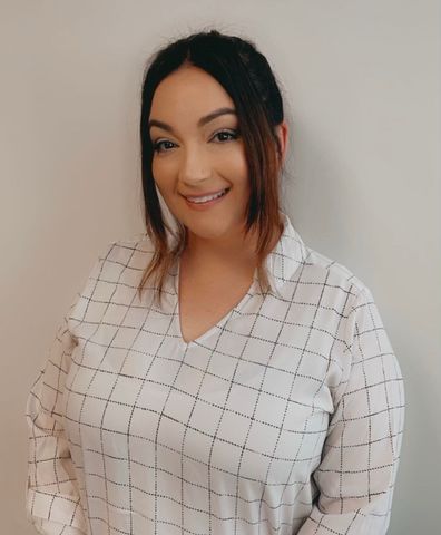 A woman in a white plaid shirt is smiling for the camera.