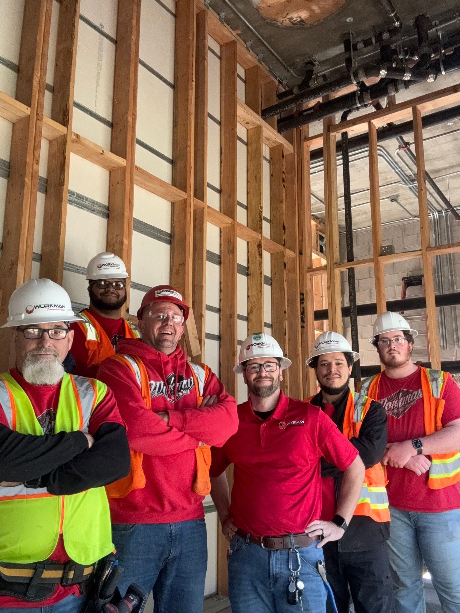 A group of construction workers are posing for a picture in a building under construction.