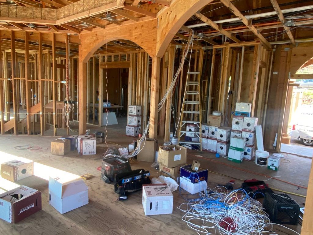 A room in a house under construction with boxes and wires on the floor.