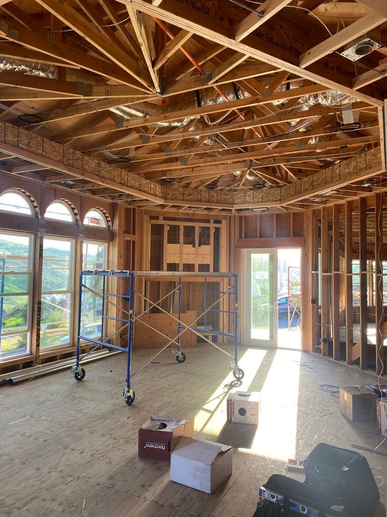 A large room under construction with a scaffolding and boxes on the floor.