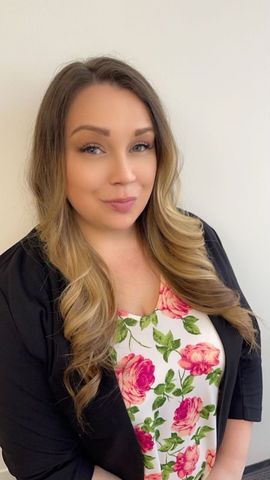 A woman with long hair is wearing a floral shirt and a black jacket.