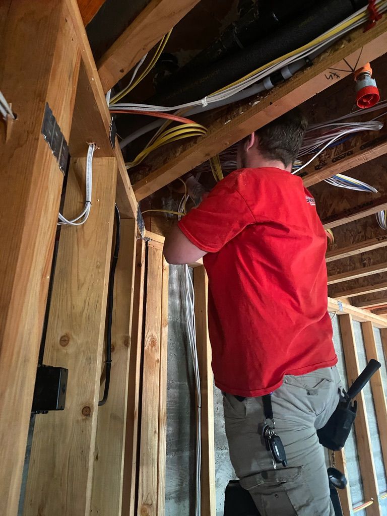 A man in a red shirt is working on the ceiling of a house.