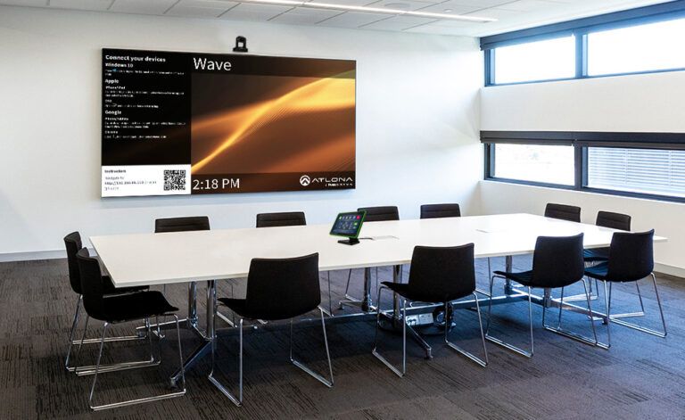 A conference room with a large screen on the wall that says wave