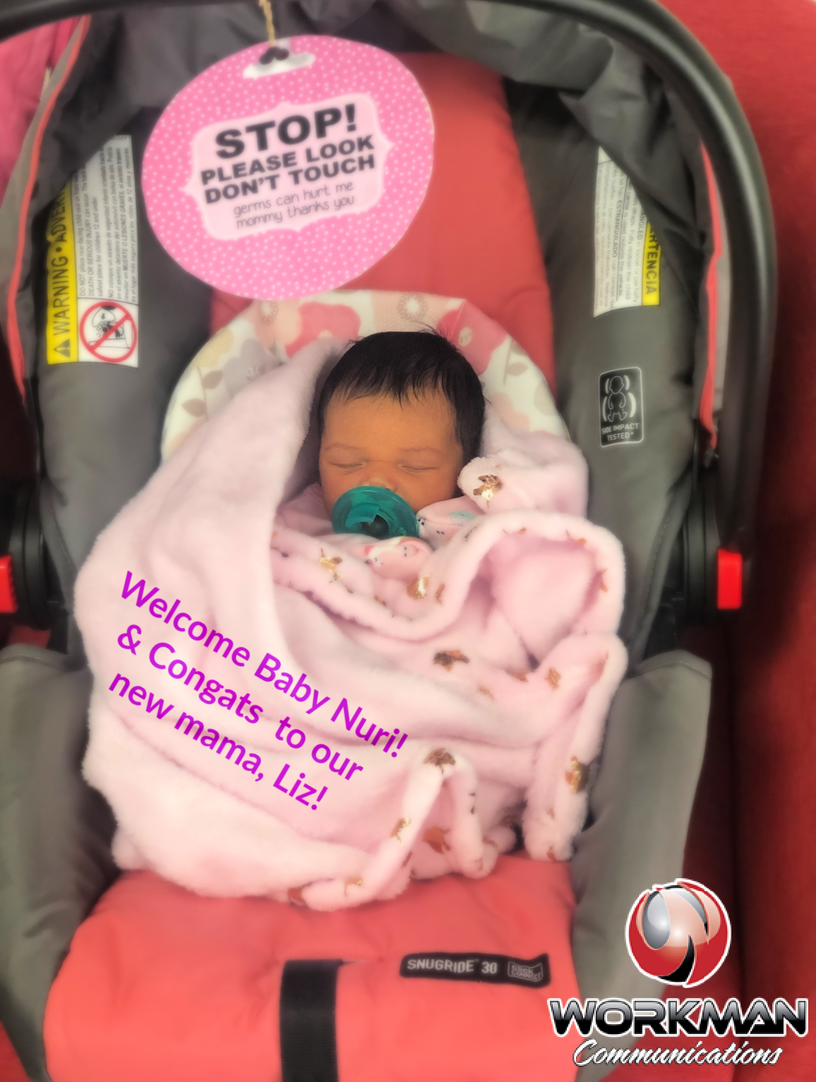 A baby is wrapped in a pink blanket in a car seat