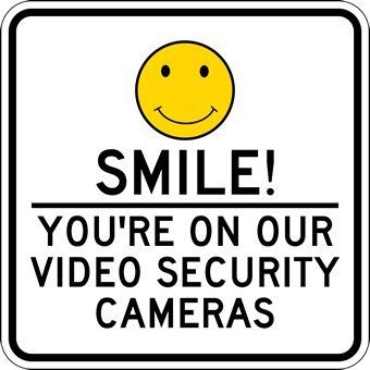 A sign that says `` smile ! you 're on our video security cameras '' with a smiley face.