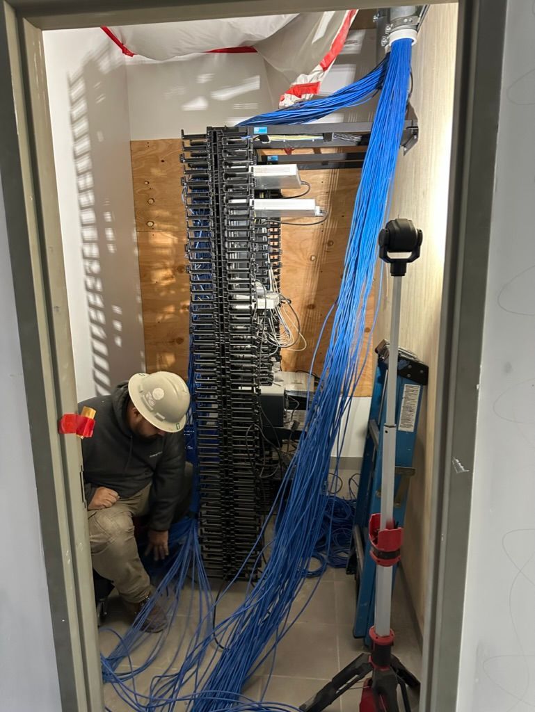 A man is sitting in a room with a lot of wires on the floor.