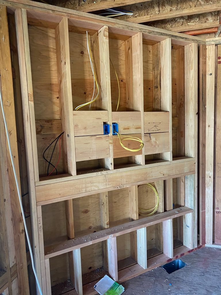 A wooden wall with shelves and wires coming out of it.