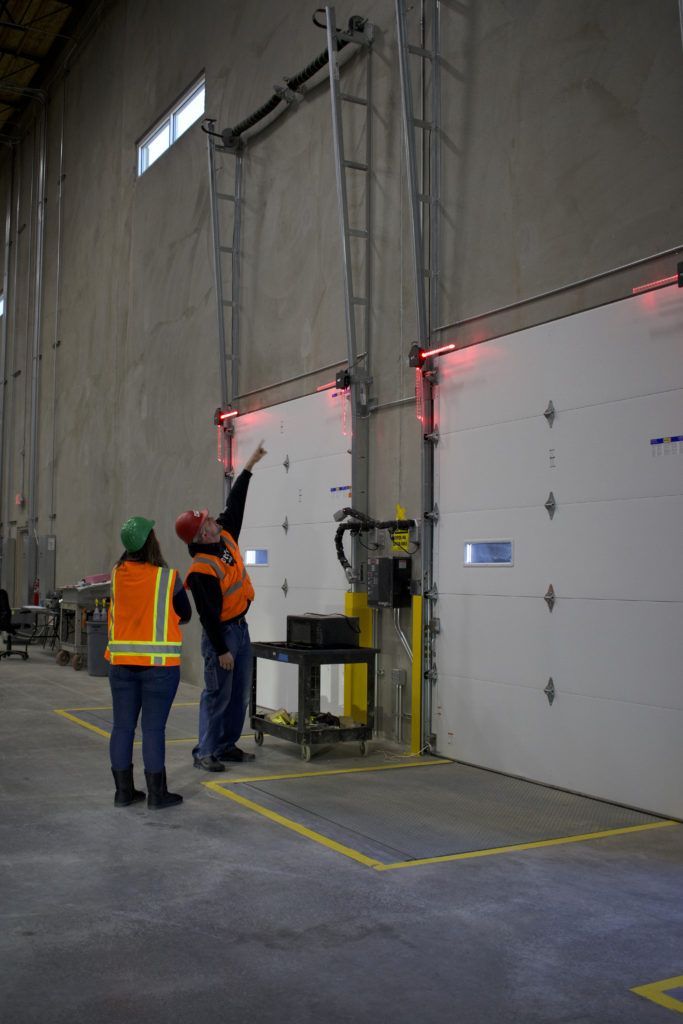 A man and a woman are standing in a warehouse looking at a door.