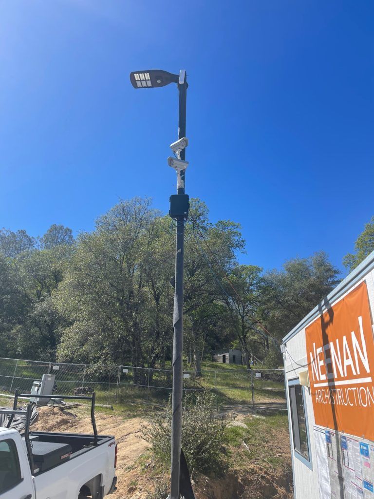 A truck is parked next to a pole with a camera on it.