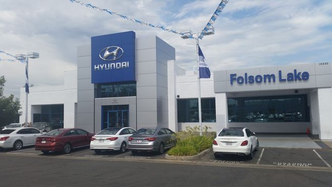 A hyundai dealership with cars parked in front of it.