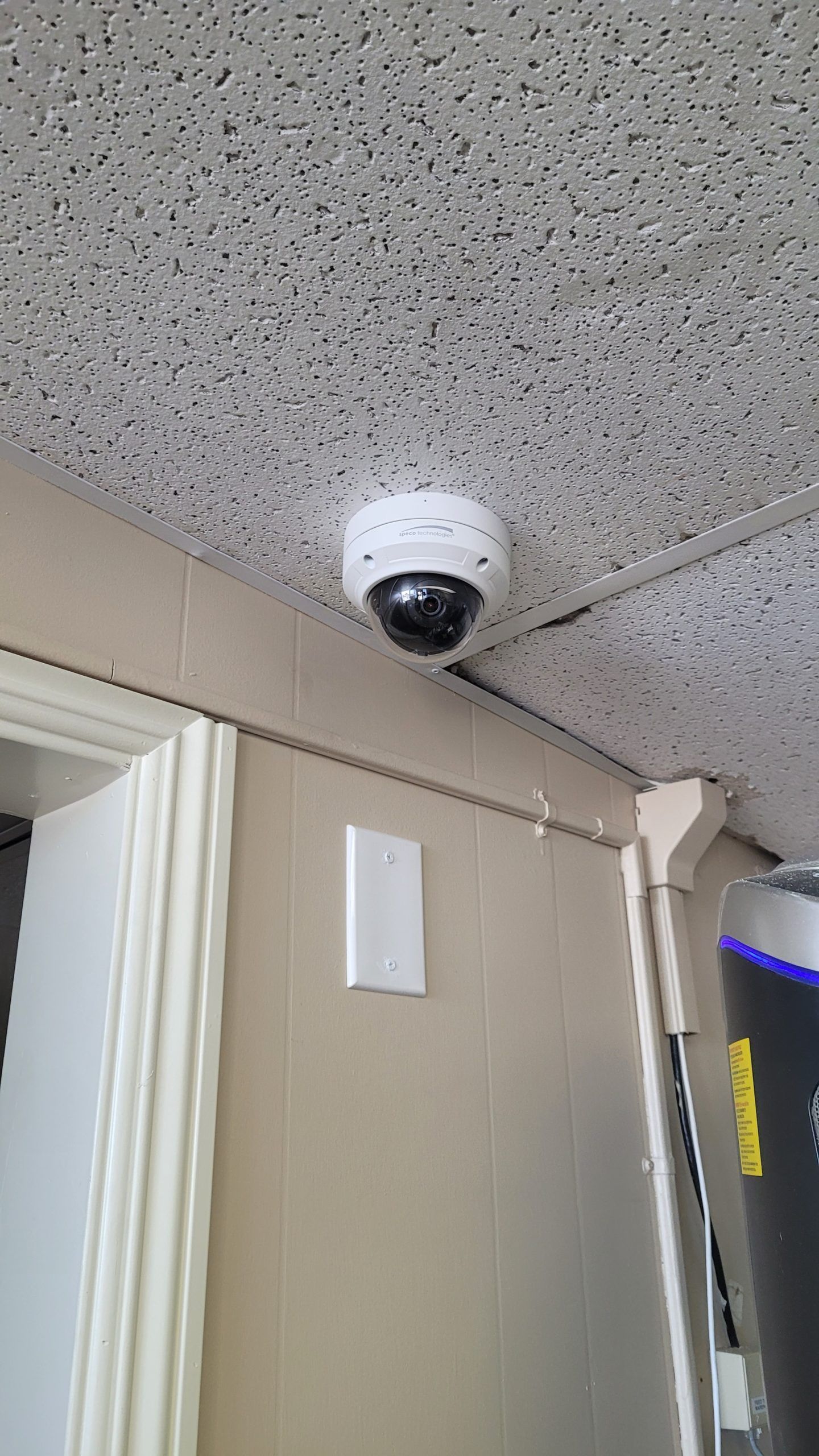 A security camera is mounted to the ceiling of a room.