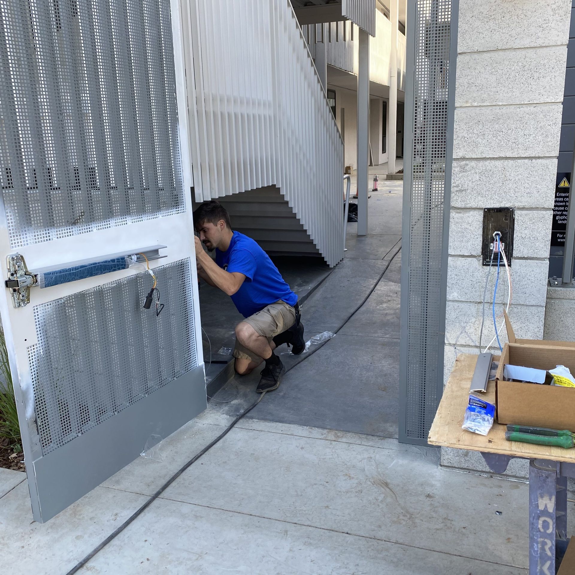 A man in a blue shirt is working on a gate