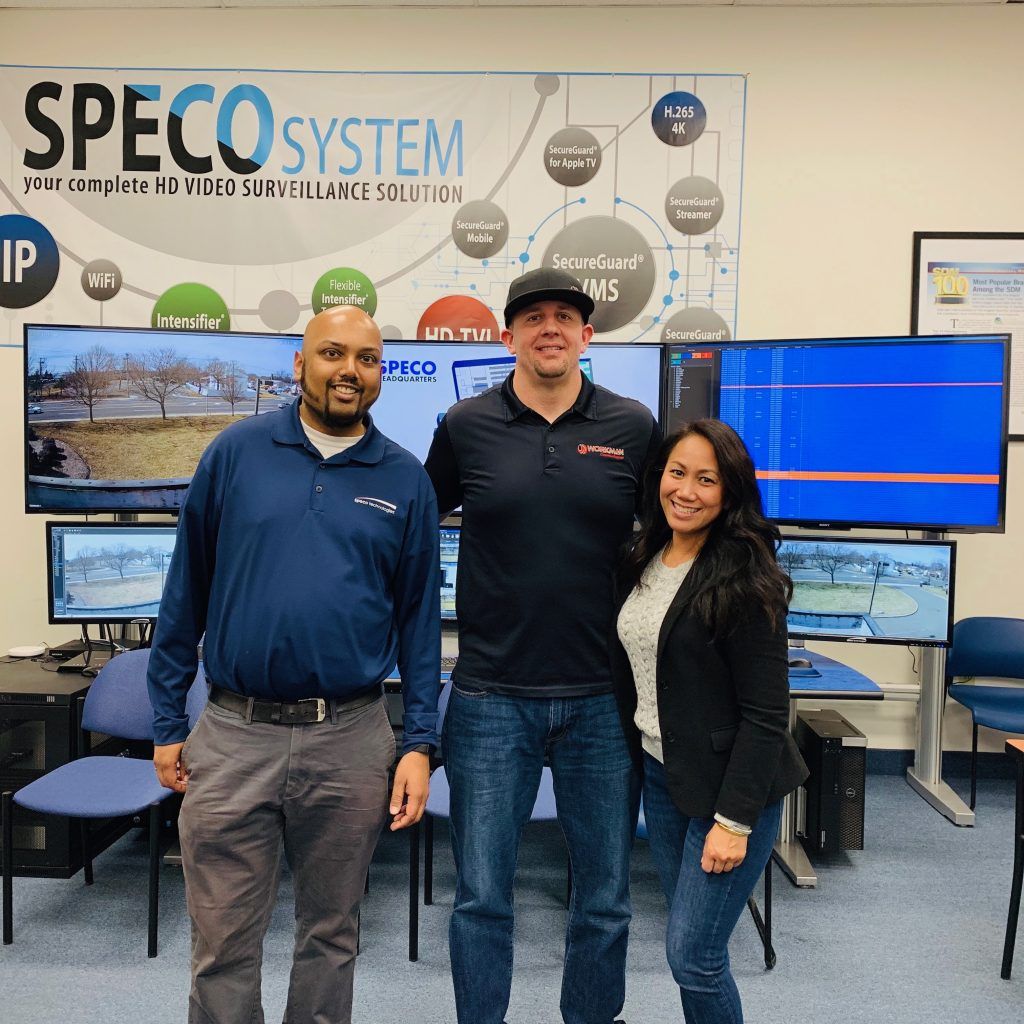 Three people standing in front of a speco system sign