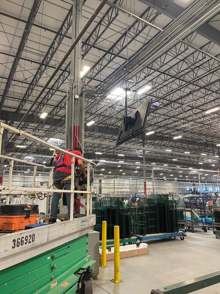 A man is working on a crane in a large warehouse.