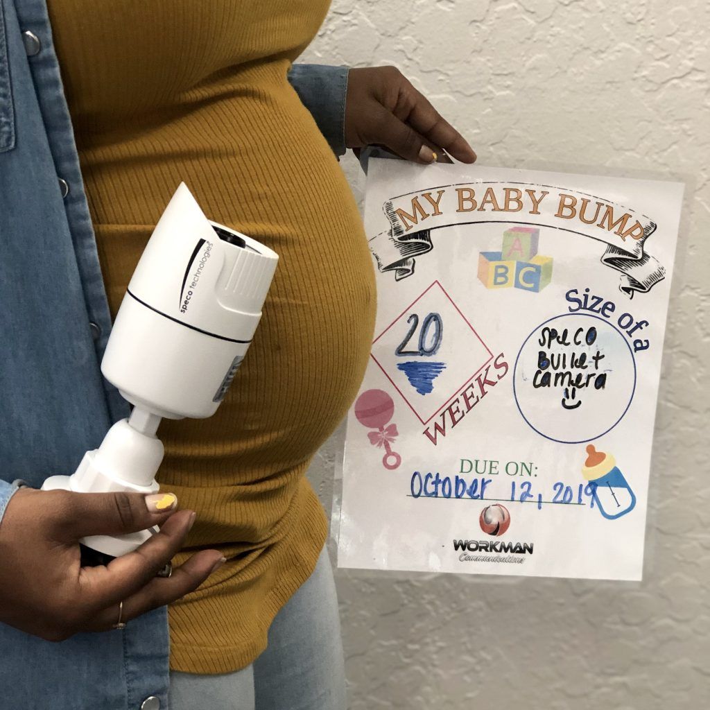 A pregnant woman is holding a camera and a sign that says my baby bump