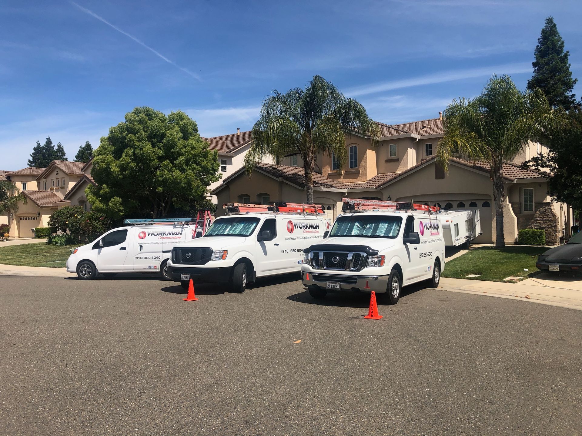 Three white vans are parked in front of a house.