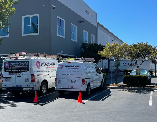 Two white vans are parked in front of a building