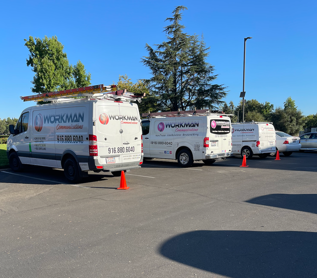 Three workman vans are parked in a parking lot