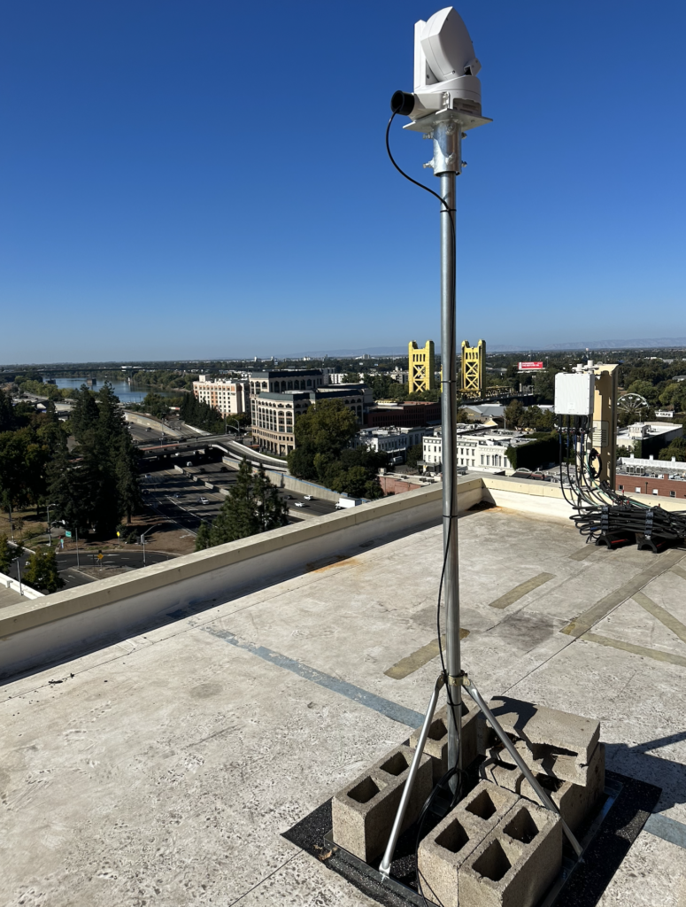 A camera is sitting on top of a pole on a roof.