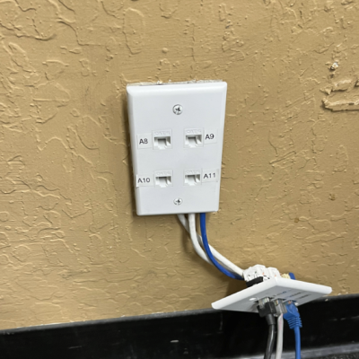 A white electrical outlet on a wall with wires coming out of it.