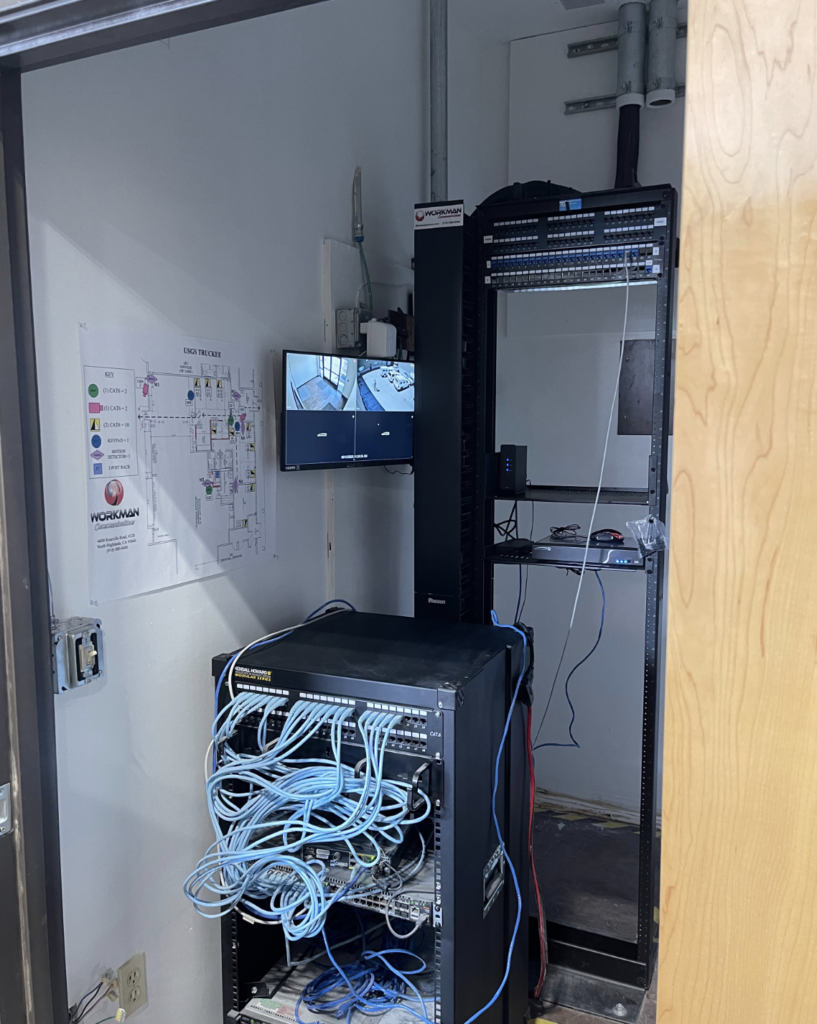 A room with a lot of wires hanging from the ceiling and a tv on the wall.