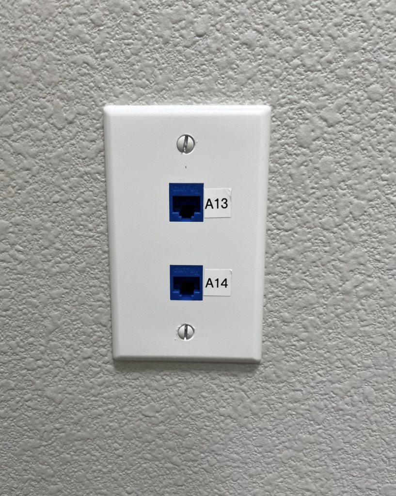 A white wall plate with two ethernet ports on it.