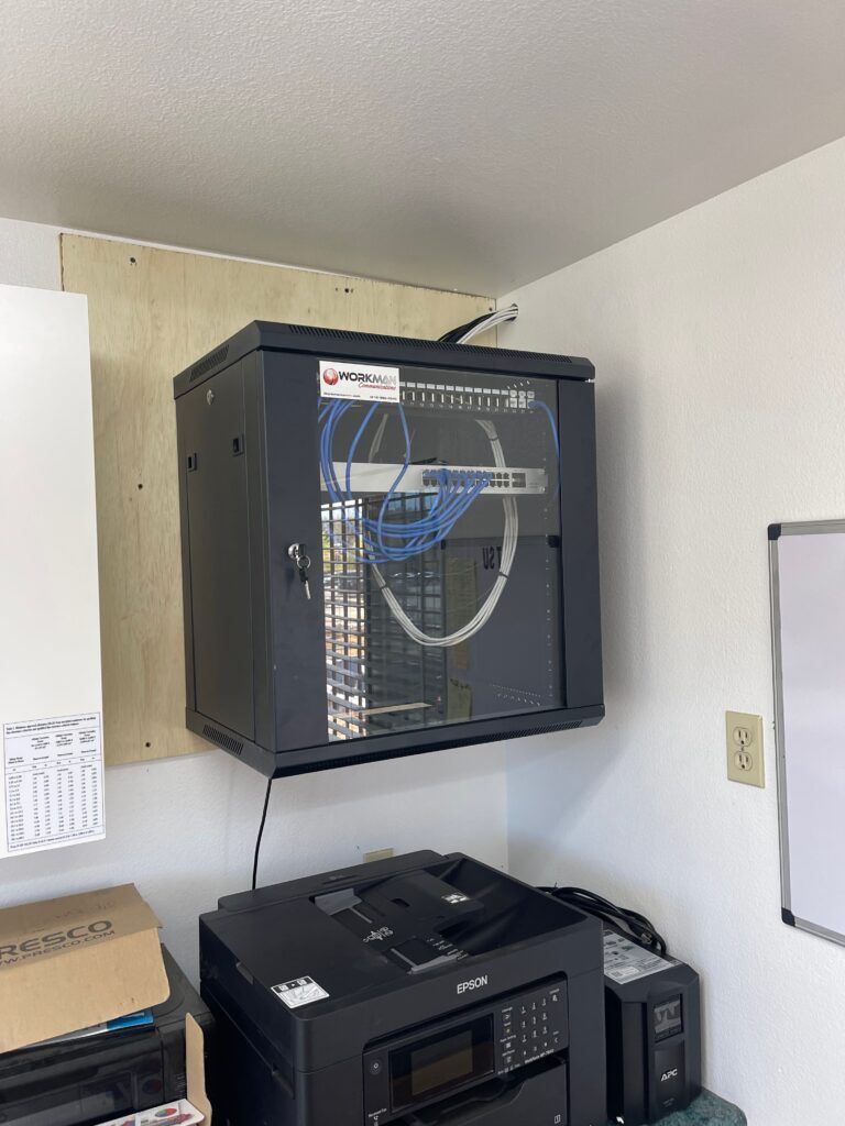 A server cabinet is hanging from the ceiling in a room next to a printer.