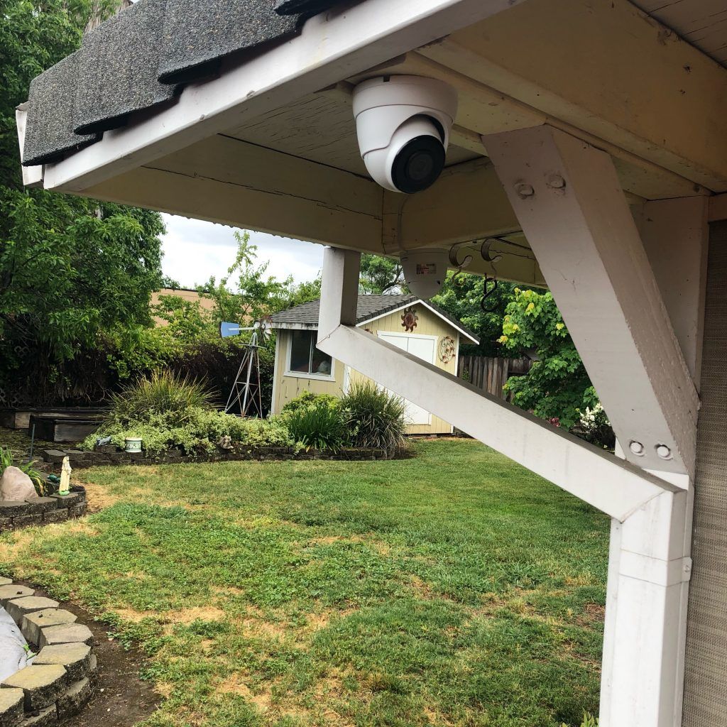 A security camera is mounted on the side of a house.