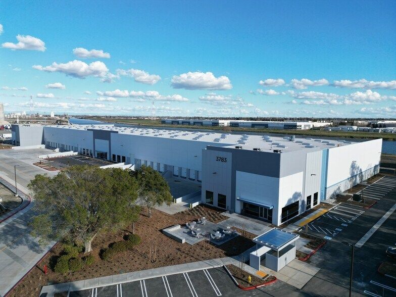 An aerial view of a large warehouse with a parking lot in front of it.