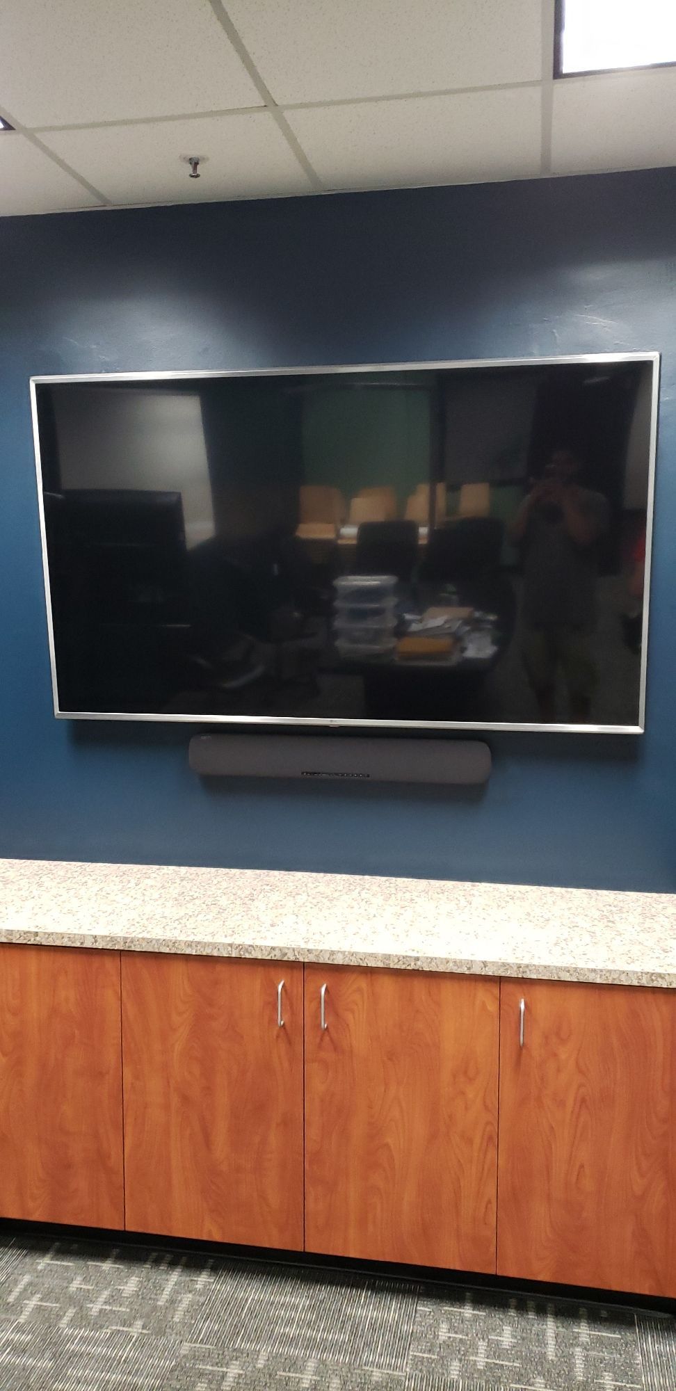 A large flat screen tv is mounted on a wall above a counter.