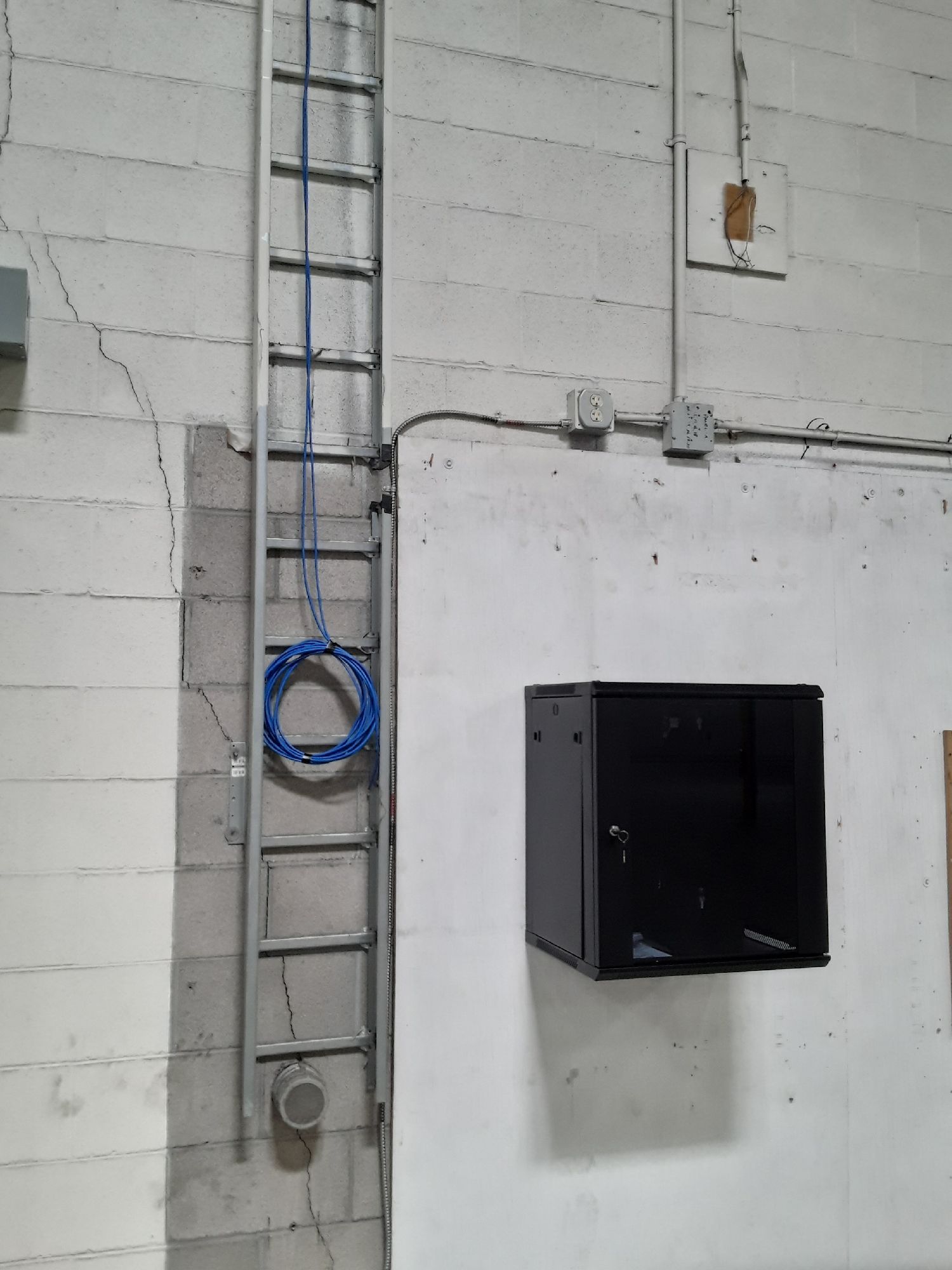 A ladder is attached to a wall next to a black box