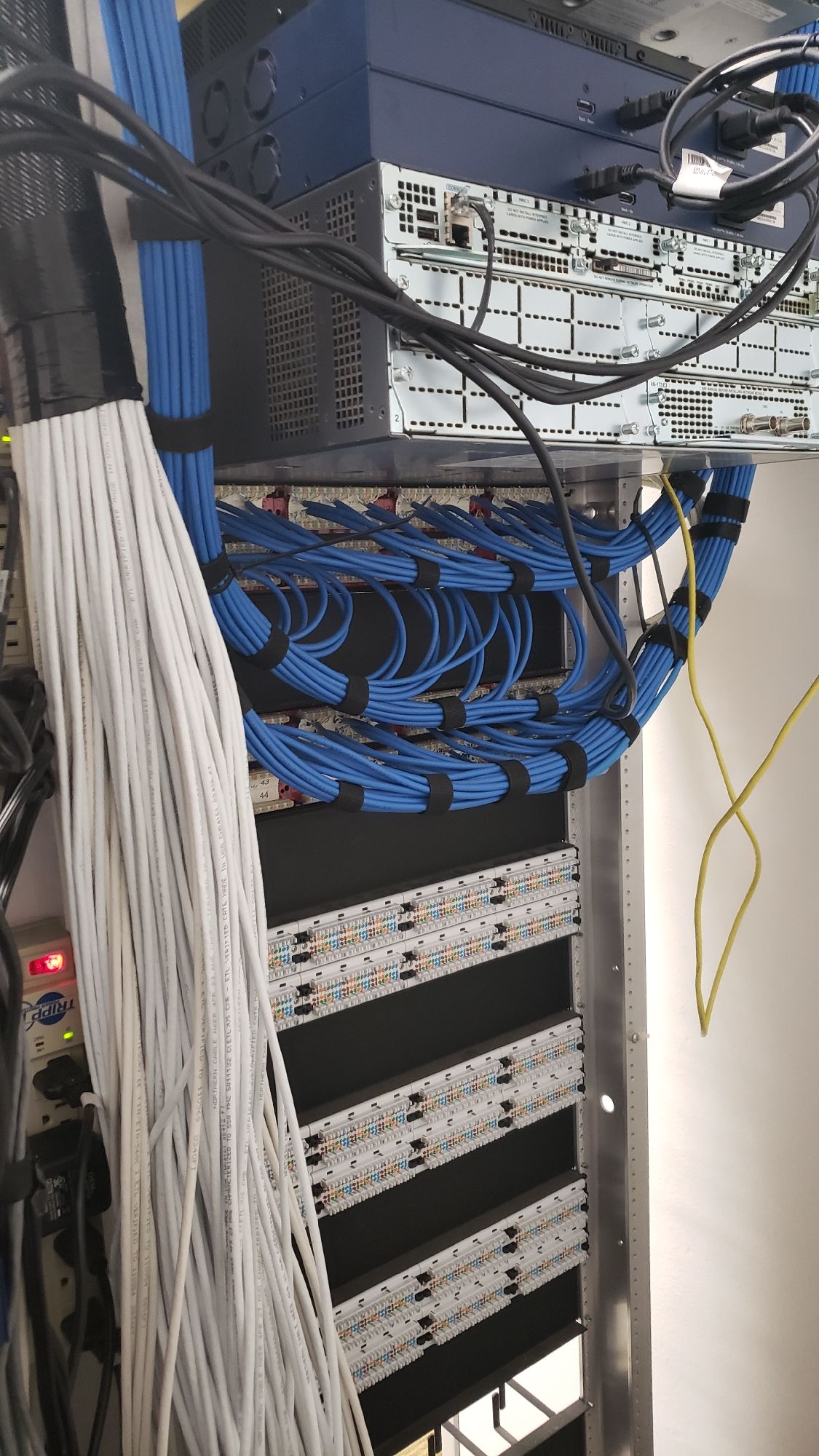 A bunch of wires are hanging from the ceiling of a server rack.