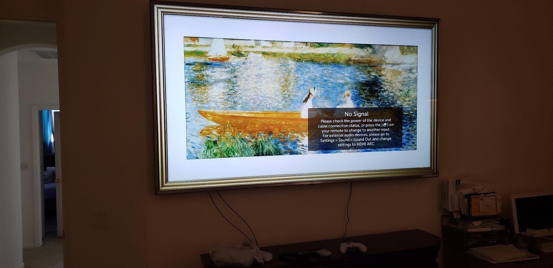 A large flat screen tv is hanging on a wall with a picture on it.