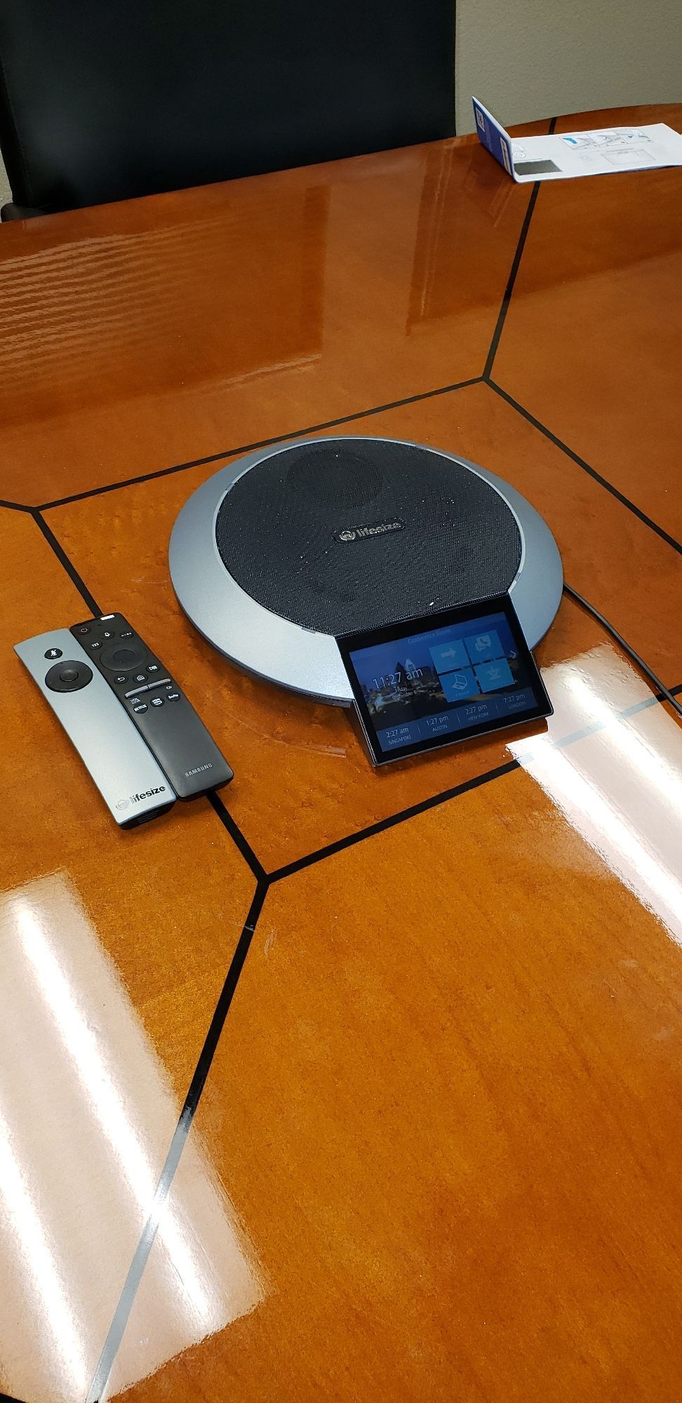 A speaker and remote control are on a wooden table.