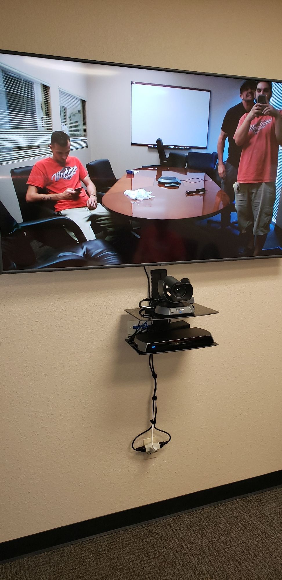 A large flat screen tv is hanging on a wall in a conference room.