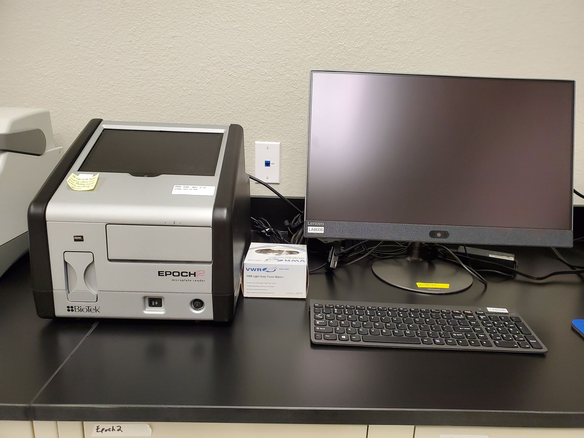 A computer is sitting on a desk next to a printer and keyboard.