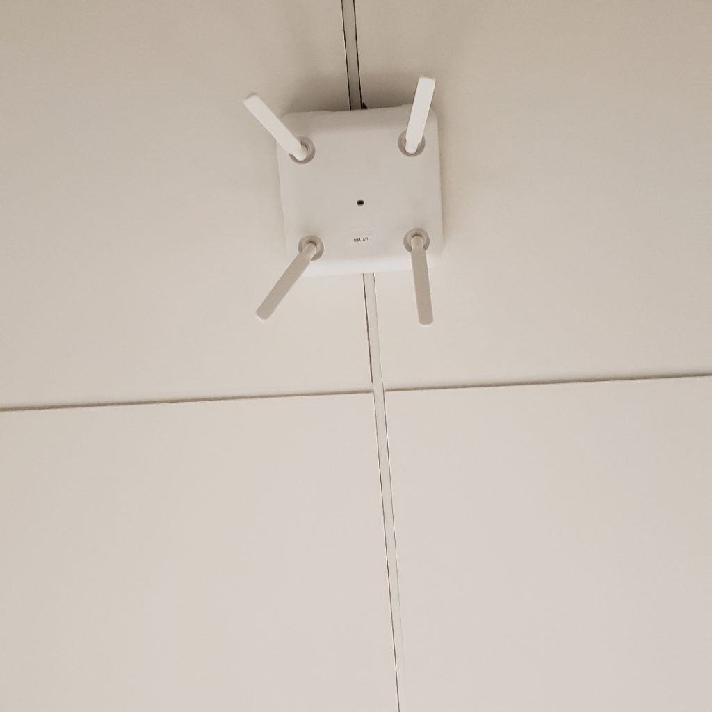 A white ceiling mounted device with three antennas attached to it