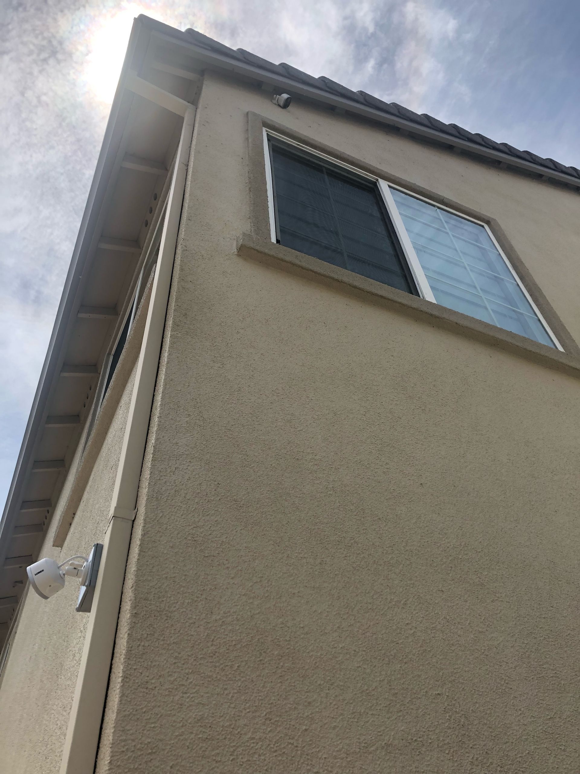 Looking up at the corner of a house with a window.