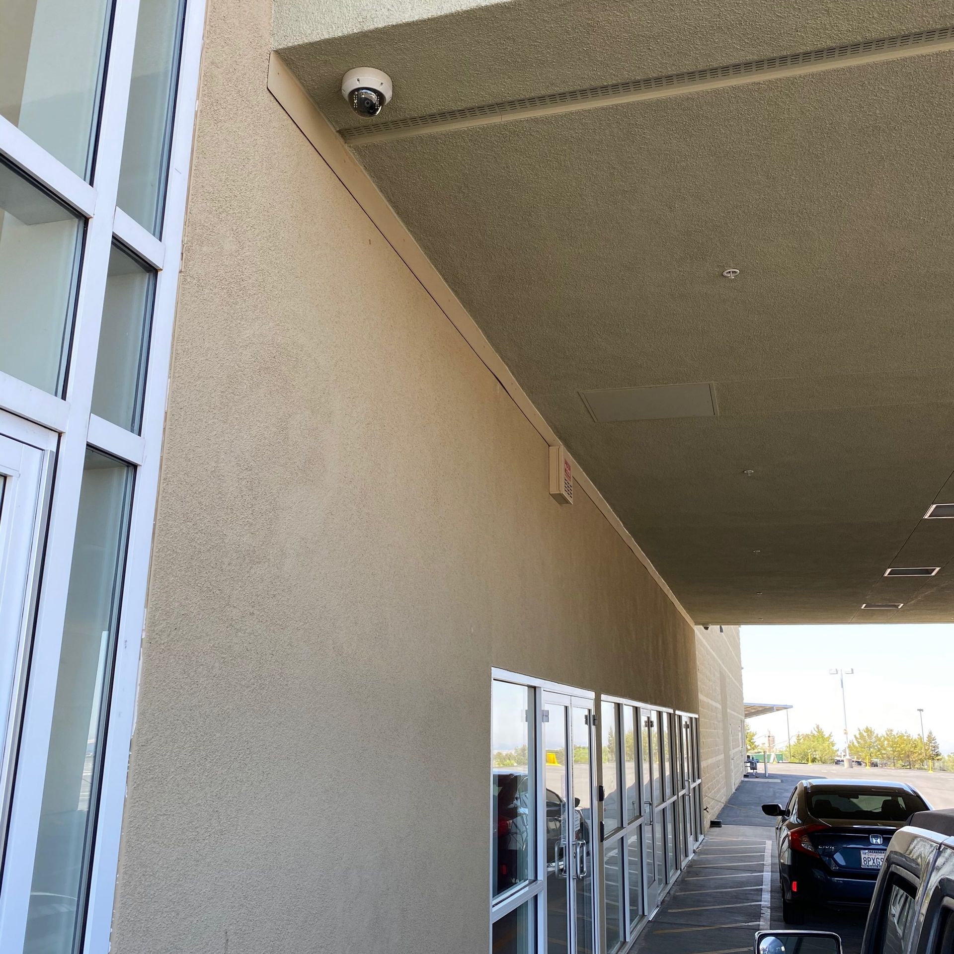 A car is parked under a covered walkway in front of a building